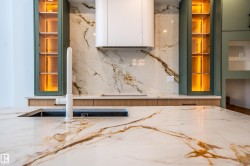 Kitchen view of light stone countertops, glass insert cabinets, white cabinets, and green cabinets - 