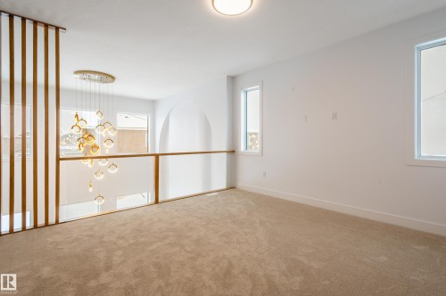 Carpeted spare room featuring a chandelier and baseboards - 43 Eldridge Point(E), St. Albert, AB - Indoor Photo Showing Other Room