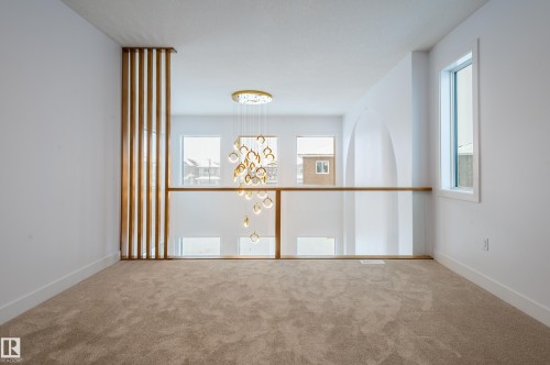 Carpeted spare room featuring a chandelier and baseboards - 43 Eldridge Point(E), St. Albert, AB - Indoor Photo Showing Other Room