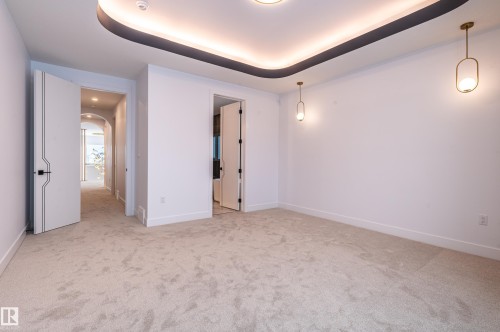 Unfurnished bedroom with arched walkways, light colored carpet, and a tray ceiling - 43 Eldridge Point(E), St. Albert, AB - Indoor Photo Showing Other Room