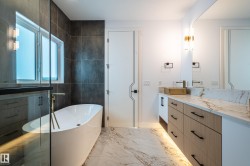 Full bath featuring a soaking tub, light marble finish flooring, and vanity - 