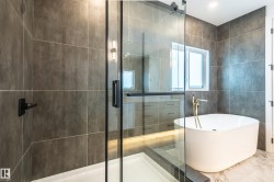 Bathroom featuring a soaking tub, marble tiled floors, a shower stall, and tile walls - 