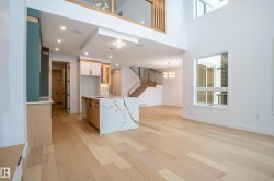 Kitchen with light wood-type flooring, a chandelier, light stone counters, a towering ceiling, and open floor plan - 