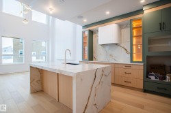 Kitchen with light brown cabinetry, tasteful backsplash, light wood-type flooring, recessed lighting, and light stone counters - 