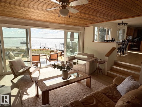 Sunroom / solarium featuring wood ceiling, a water view, healthy amount of natural light, and wood finished floors - A15 Wicks Street, Rural Leduc County, AB - Indoor