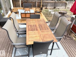 Wooden terrace featuring a fenced backyard, an outdoor living space with a fire pit, and outdoor dining space - 