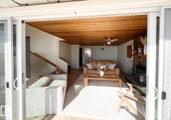 Living room with wood ceiling, a wood stove, a ceiling fan, wood finished floors, and stairway - 