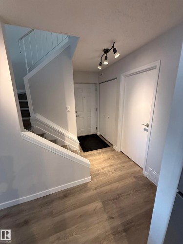 Foyer featuring light wood-style floors, stairs, and rail lighting. DSoor to the right is entrance to the mechanical room. - 23 Lancaster Terrace, Edmonton, AB - Indoor Photo Showing Other Room