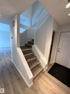 Stairs featuring wood finished floors and baseboards. Living room and door to the private deck off to the left. - 