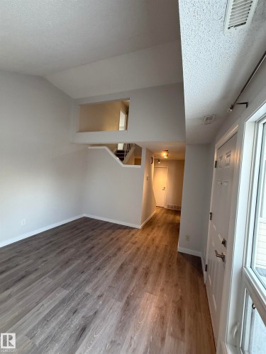 Spacious living room with a cathedral ceiling, LVP finished floors, and stairs - 23 Lancaster Terrace, Edmonton, AB - Indoor Photo Showing Other Room