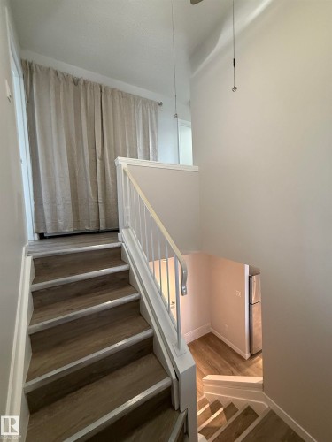 Stairs with Wood style LVP finished floors and baseboards. Laundry centre behind the curtain. - 23 Lancaster Terrace, Edmonton, AB - Indoor Photo Showing Other Room