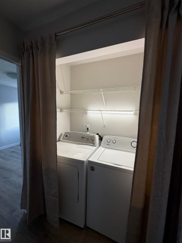 Well lit Laundry area with dark wood-style LVP floors and washer and clothes dryer - 23 Lancaster Terrace, Edmonton, AB - Indoor Photo Showing Laundry Room