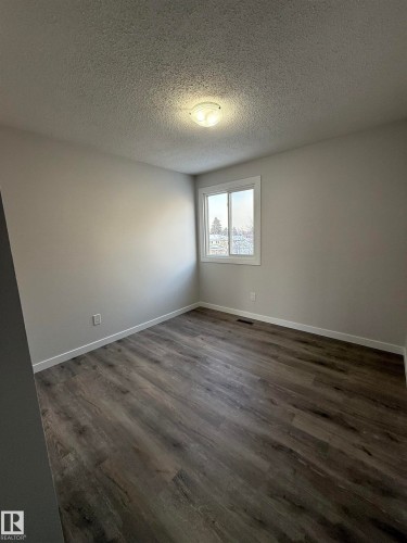 Bedroom 3 featuring a textured ceiling and dark LVP wood style finished floors - 23 Lancaster Terrace, Edmonton, AB - Indoor Photo Showing Other Room