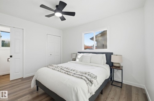 Bedroom featuring wood finished floors, fresh paint, and ceiling fan. Closet and ensuite half bath with pocket door. - 13507 124 Avenue, Edmonton, AB - Indoor Photo Showing Bedroom