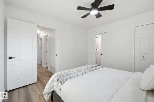Bedroom featuring wood finished floors, fresh paint, and ceiling fan. Closet and ensuite half bath with pocket door. - 13507 124 Avenue, Edmonton, AB - Indoor Photo Showing Bedroom