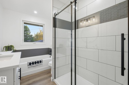 Bathroom featuring black accents, new vanity, a tub and a shower, light wood-style floors, and recessed lighting. - 13507 124 Avenue, Edmonton, AB - Indoor