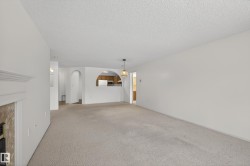 Unfurnished living room with a textured ceiling, carpet, arched walkways, and a premium fireplace - 