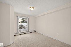 Empty room with a baseboard radiator, a textured ceiling, and light carpet - 