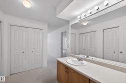Bathroom with a closet, vanity, light carpet, and a textured ceiling - 