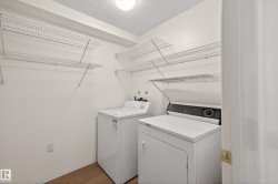 Laundry area with a textured ceiling, wood finished floors, and washer and clothes dryer - 