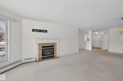 Unfurnished living room featuring carpet, a high end fireplace, a textured ceiling, arched walkways, and a baseboard radiator - 