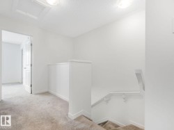 Hall with an upstairs landing, light carpet, attic access, and a textured ceiling - 