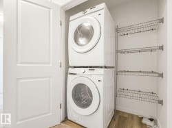 Laundry area with stacked washer and clothes dryer and light wood-type flooring - 