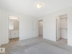 Unfurnished bedroom featuring light carpet, a walk in closet, and connected bathroom - 