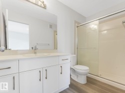 Full bathroom featuring vanity, light wood finished floors, a shower stall, and a textured ceiling - 