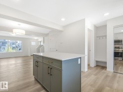 Kitchen featuring a center island, light wood-style flooring, appliances with stainless steel finishes, gray cabinetry, and hanging light fixtures - 