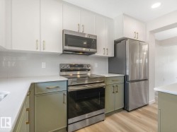 Kitchen featuring appliances with stainless steel finishes, backsplash, and white cabinets - 