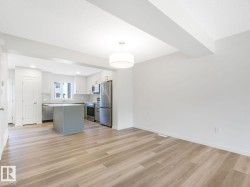 Kitchen with hanging light fixtures, open floor plan, appliances with stainless steel finishes, a center island, and white cabinetry - 