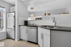 Kitchen featuring pendant lighting, appliances with stainless steel finishes, decorative backsplash, white cabinetry, and a textured ceiling - 