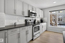 Kitchen featuring stainless steel appliances, a textured ceiling, backsplash, and light wood-style floors - 