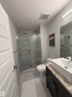 Bathroom with light marble finish floors, vanity, a marble finish shower, and a textured ceiling - 