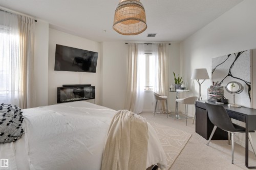 221 6083 Maynard Way, Edmonton, AB - Indoor Photo Showing Bedroom With Fireplace