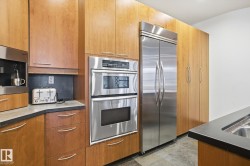 Kitchen with stainless steel appliances, modern cabinets, brown cabinetry, and stone finish flooring - 