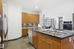 Kitchen with brown cabinetry, freestanding refrigerator, open floor plan, a kitchen island with sink, and tasteful backsplash - 