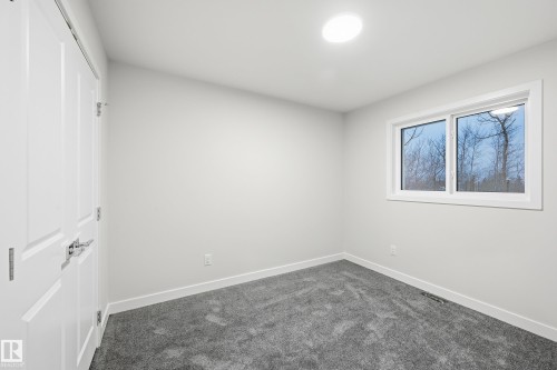 Unfurnished bedroom with a closet and dark colored carpet - 53 Patriot Way, Spruce Grove, AB - Indoor Photo Showing Other Room