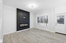 Foyer entrance with a large fireplace and light wood-style floors - 53 Patriot Way, Spruce Grove, AB  - Indoor Photo Showing Other Room With Fireplace 