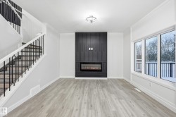 Unfurnished living room with stairway, light wood-type flooring, and a large fireplace - 