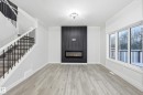 Unfurnished living room with stairway, light wood-type flooring, and a large fireplace - 53 Patriot Way, Spruce Grove, AB  - Indoor With Fireplace 