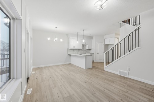 Unfurnished living room with stairway, a chandelier, and light wood-style flooring - 53 Patriot Way, Spruce Grove, AB - Indoor