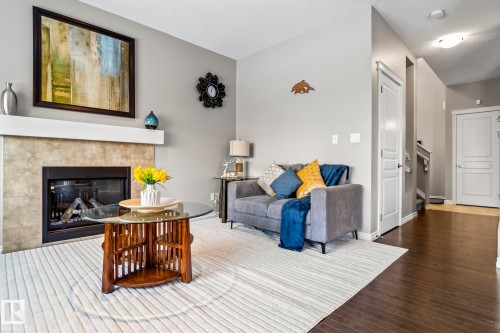 Living room with a tile fireplace, hardwood / wood-style flooring, a textured ceiling, and stairs - 5734 175A Avenue, Edmonton, AB - Indoor Photo Showing Living Room With Fireplace