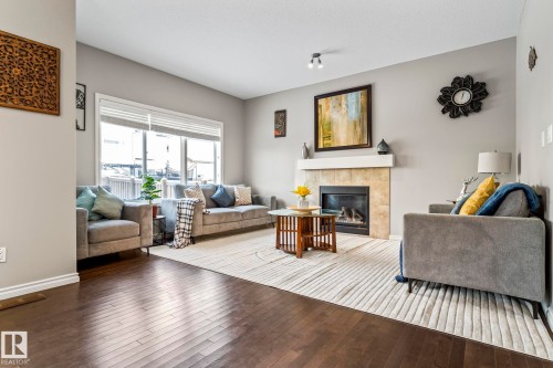 Living room with hardwood / wood-style floors and a tiled fireplace - 5734 175A Avenue, Edmonton, AB - Indoor Photo Showing Living Room With Fireplace