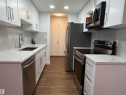 Kitchen with appliances with stainless steel finishes, light stone countertops, dark wood-style floors, white cabinets, and backsplash - 103 10511 19 Avenue, Edmonton, AB 