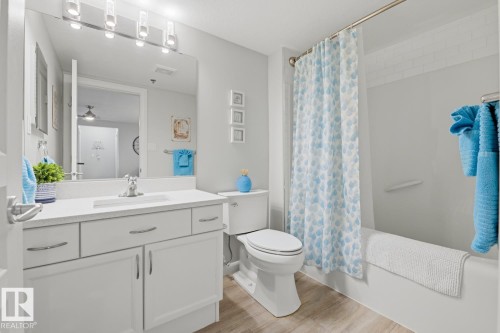 Bathroom featuring vanity, shower / tub combo with curtain, light wood-style floors, and a ceiling fan - 314 530 Hooke Road, Edmonton, AB - Indoor Photo Showing Bathroom