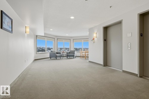 Living area featuring elevator, light carpet, recessed lighting, and a textured ceiling - 314 530 Hooke Road, Edmonton, AB - Indoor