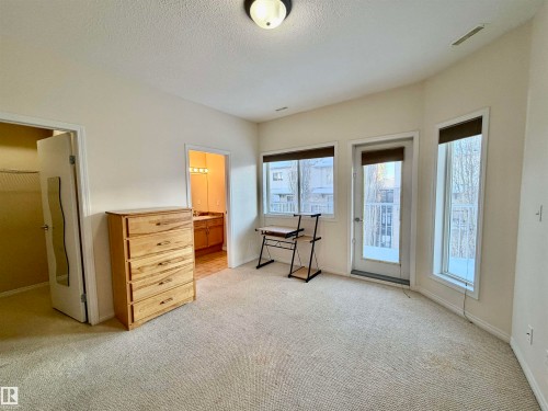 Bedroom featuring light carpet, access to outside, and a textured ceiling - 321 4304 139 Avenue, Edmonton, AB - Indoor