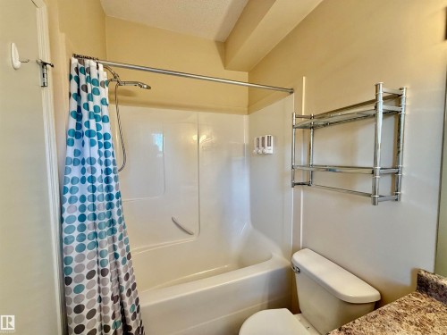 Bathroom with a textured ceiling, vanity, and shower / bath combo with shower curtain - 321 4304 139 Avenue, Edmonton, AB - Indoor Photo Showing Bathroom